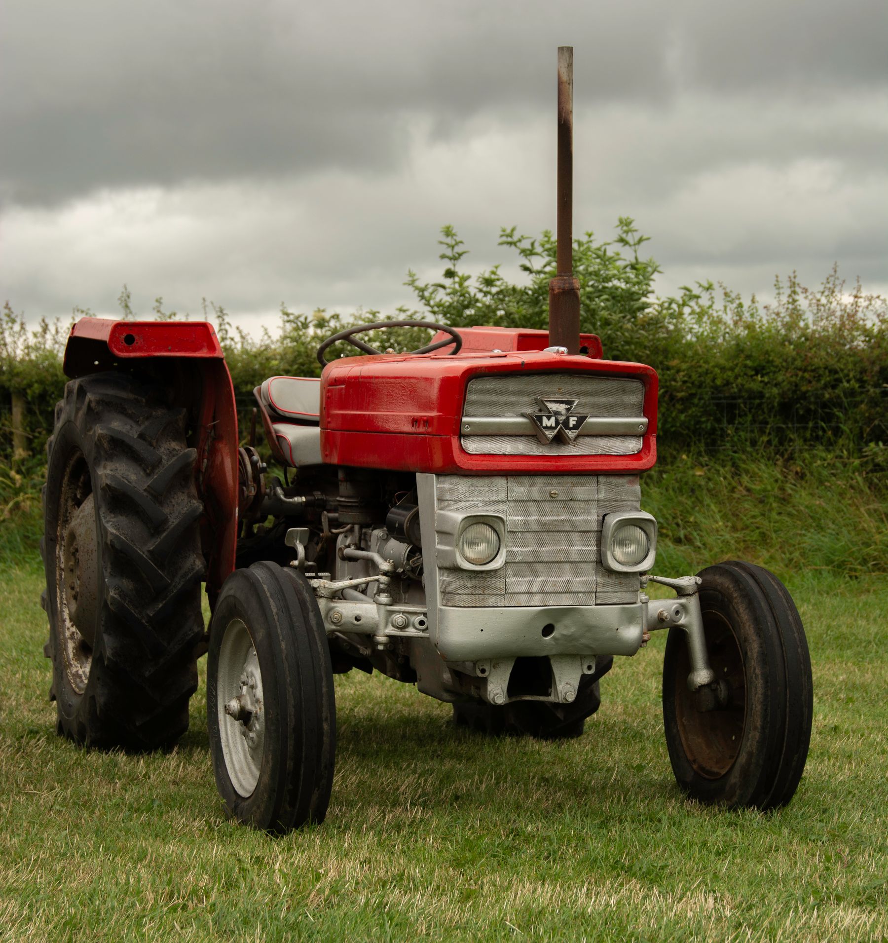 A classic red vintage tractor parked in a grassy field.